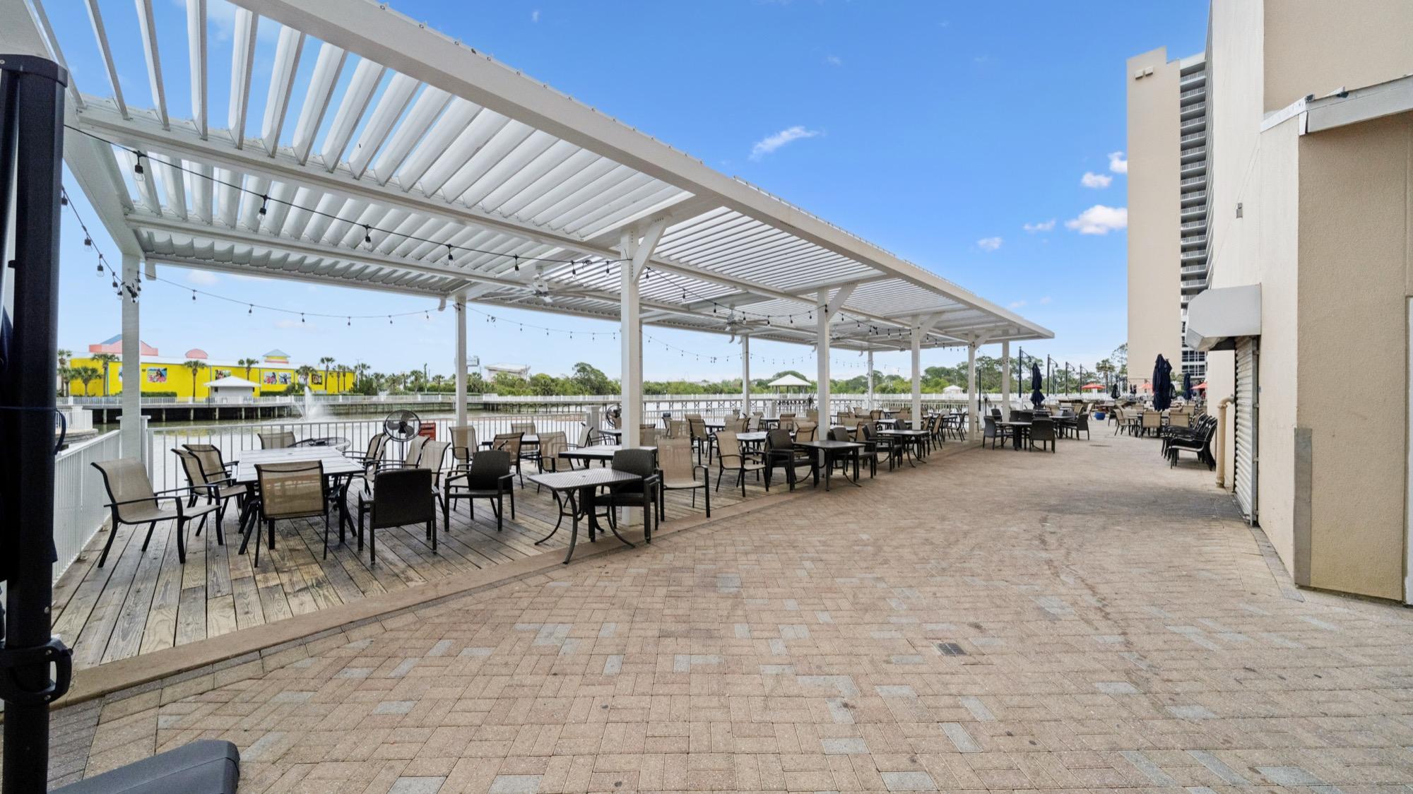 Covered rooftop patio dining with a pergola beside a condo tower, photographed on the Florida Panhandle