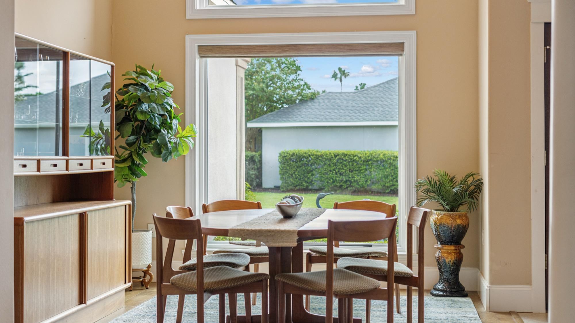 Dining nook with a round table, potted plants and a garden window view, photographed on the Florida Panhandle