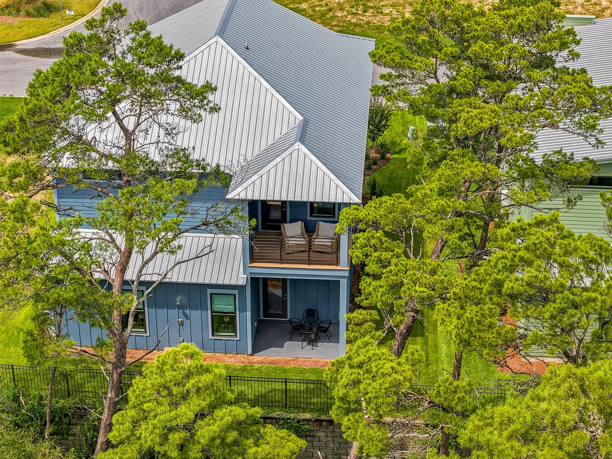 Aerial view of a gray coastal home tucked among pine trees, photographed on the Florida Panhandle