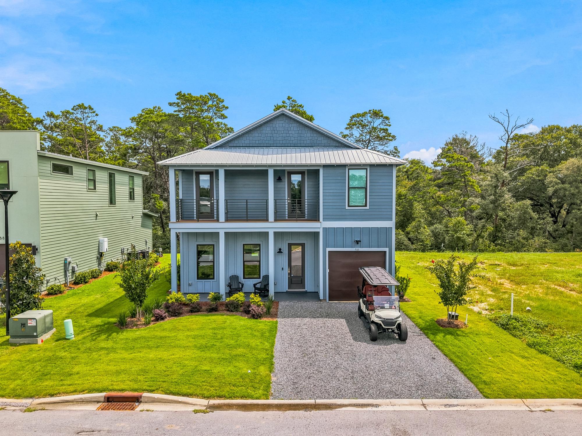 Aerial view of a new two-story home with a covered porch and golf cart, photographed on the Florida Panhandle