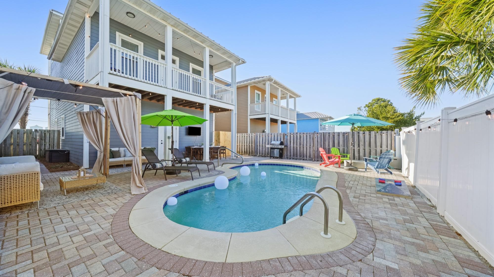 Pool deck with a canopy daybed, lounge chairs and patio umbrellas, photographed on the Florida Panhandle