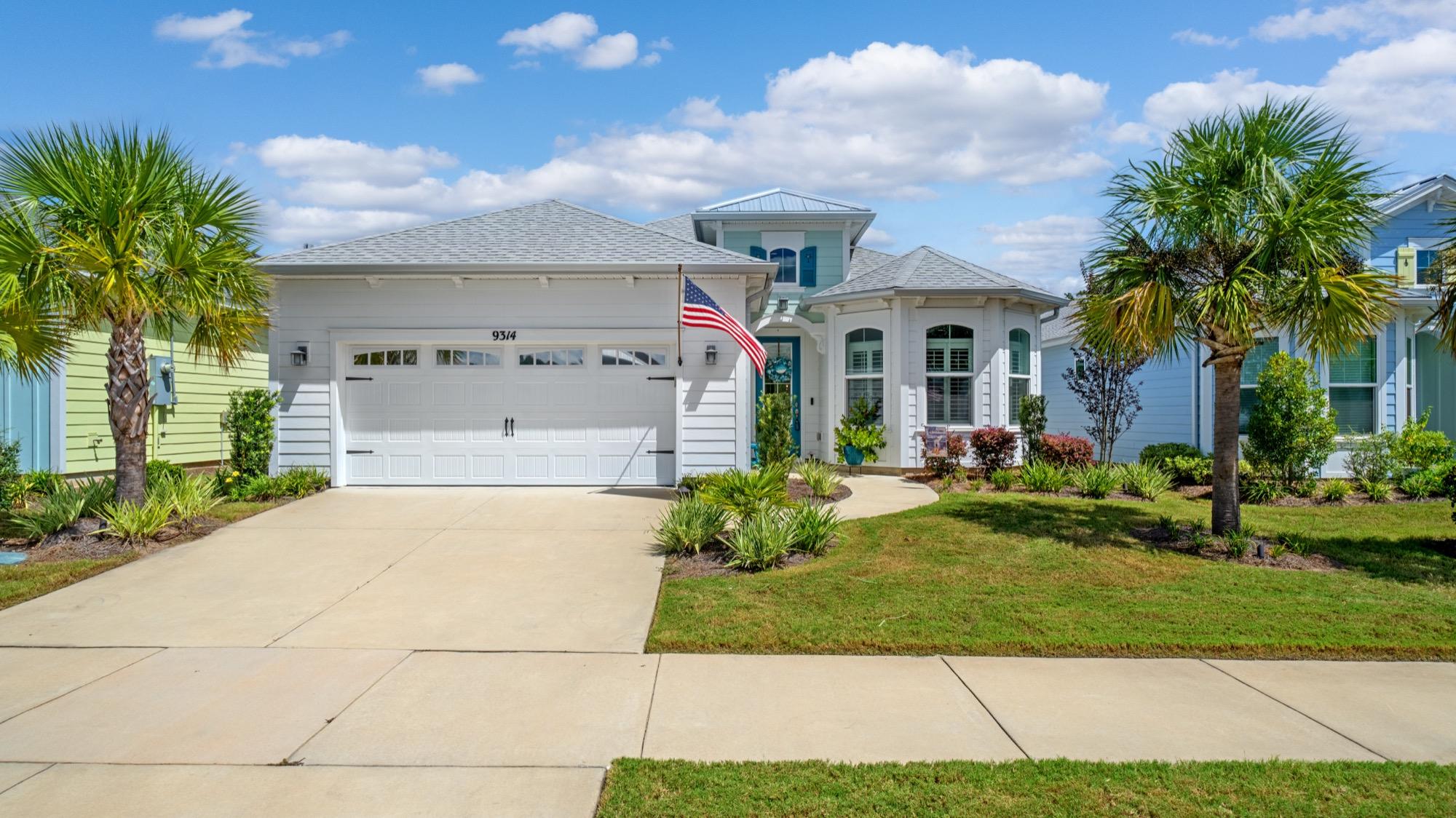 Coastal home with a two-car garage, palm trees and an American flag, photographed on the Florida Panhandle