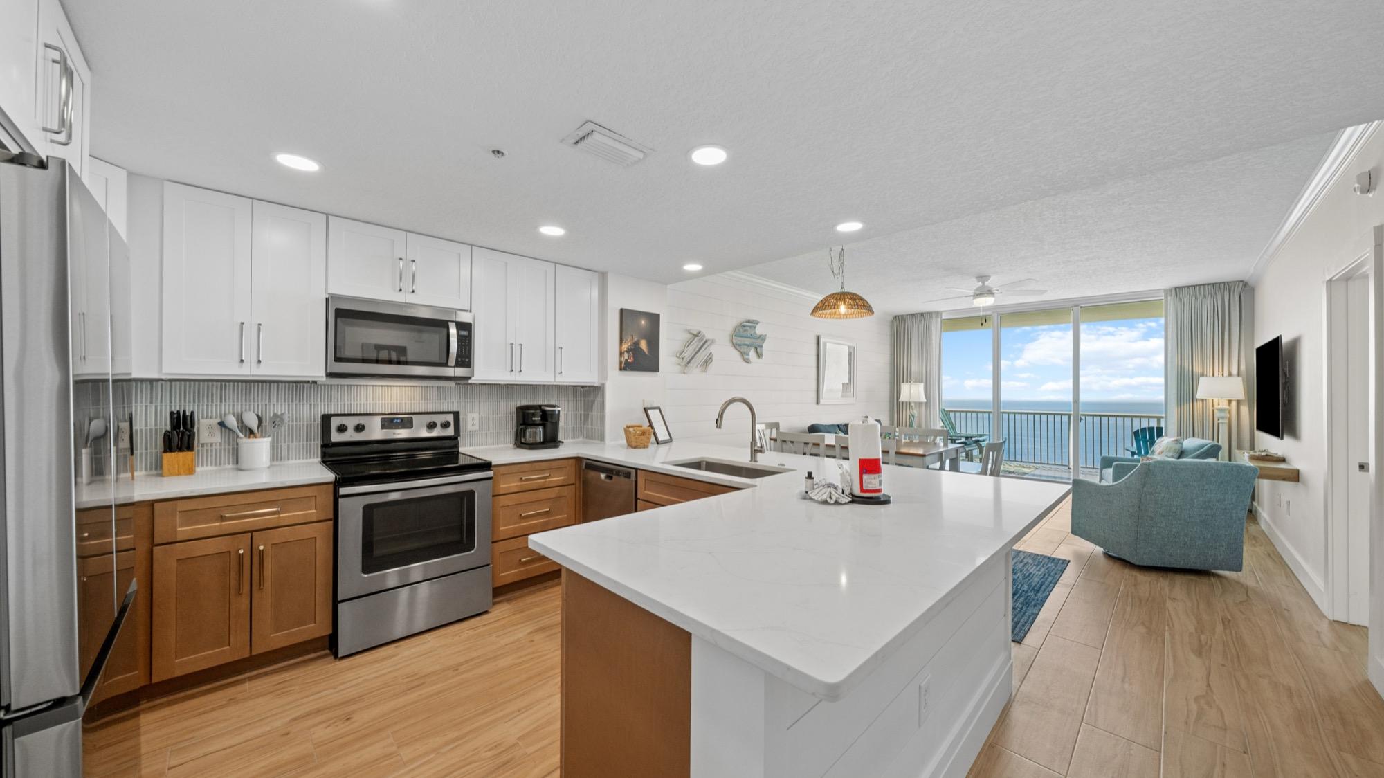 Condo kitchen with white cabinets, a quartz island and a balcony view of the Gulf, photographed on the Florida Panhandle