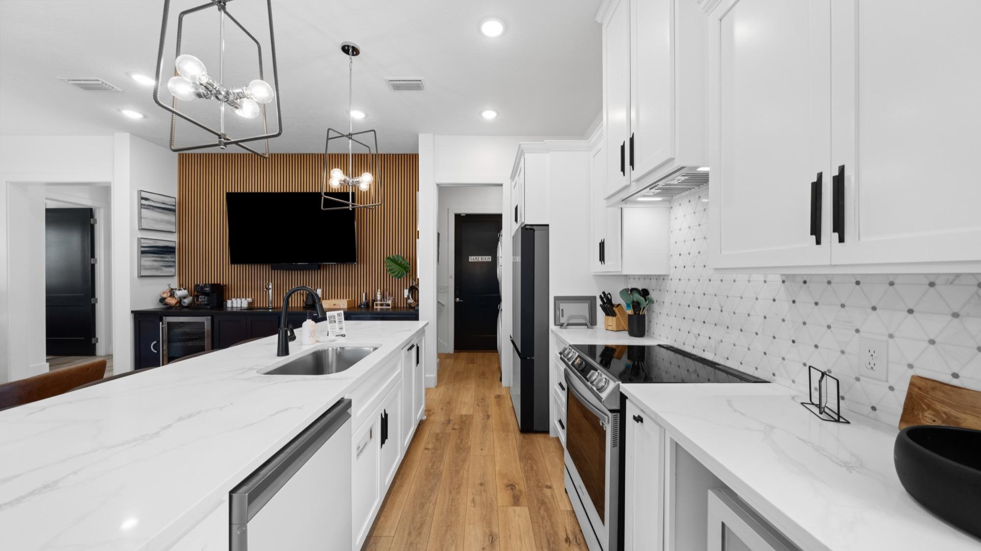 Modern white kitchen with a wood slat accent wall, matte black fixtures and an open living area, photographed on the Florida Panhandle