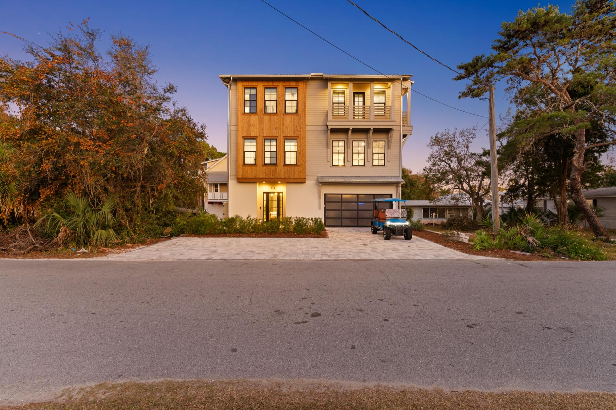 Three-story coastal home with cedar accents glowing at twilight, photographed on the Florida Panhandle