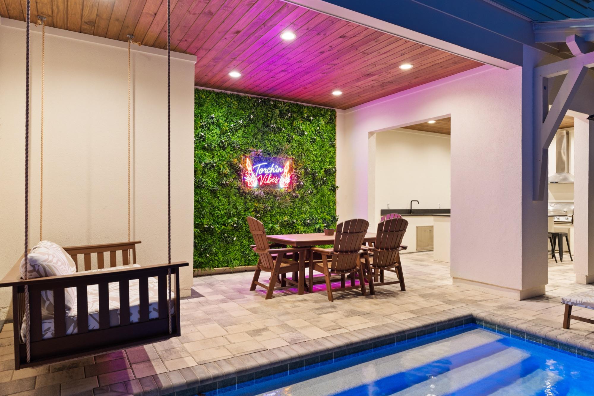 Covered patio with a porch swing, living wall and neon sign at twilight, photographed on the Florida Panhandle