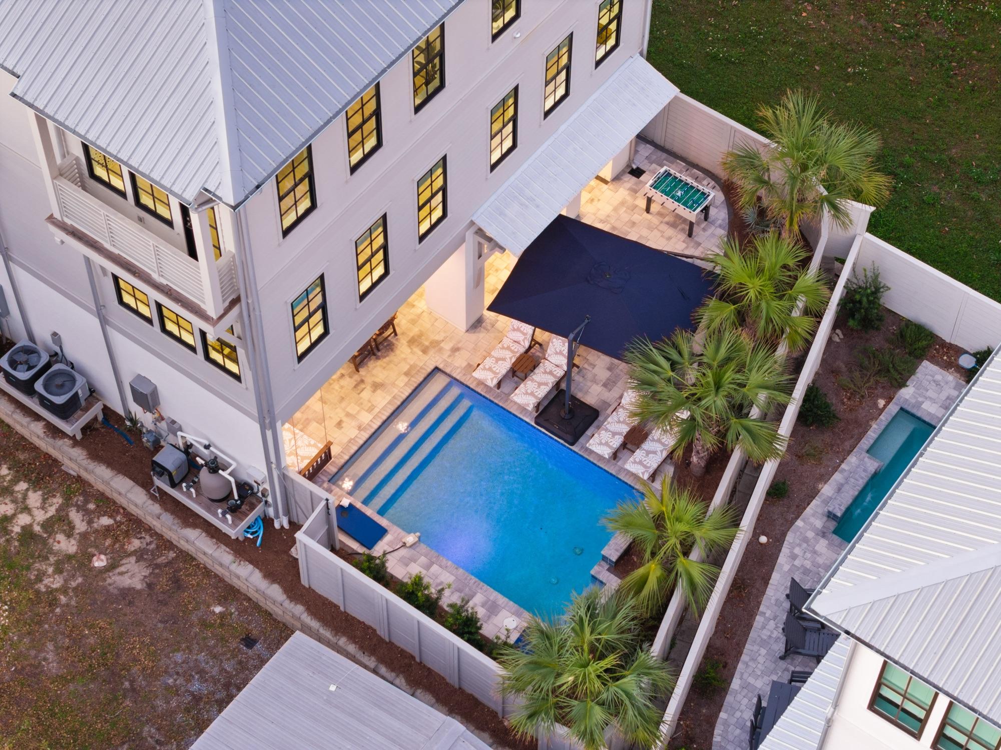 Twilight drone view of a backyard pool and patio, photographed on the Florida Panhandle