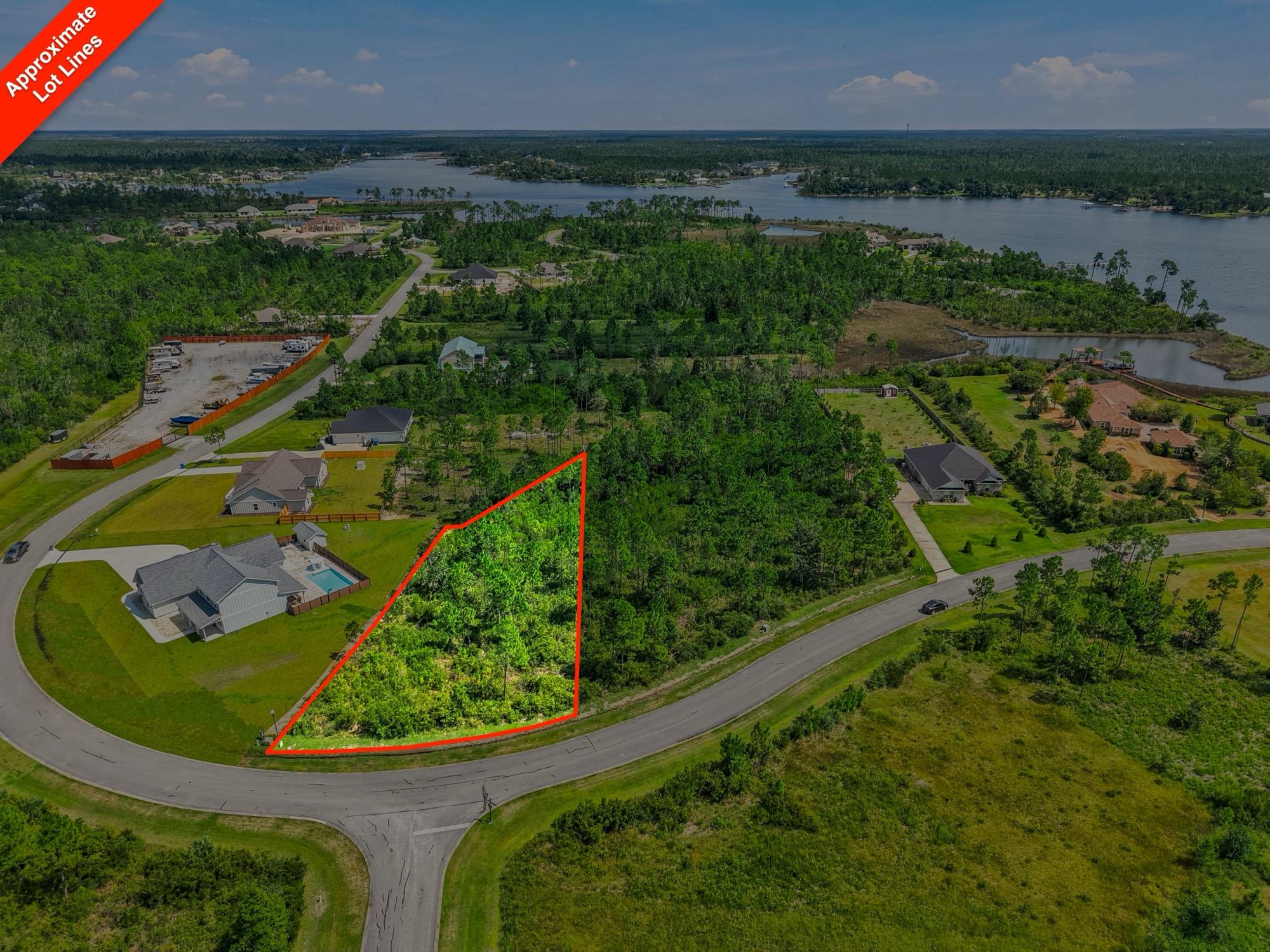 Aerial view of a wooded vacant lot outlined in red near a lake, photographed on the Florida Panhandle