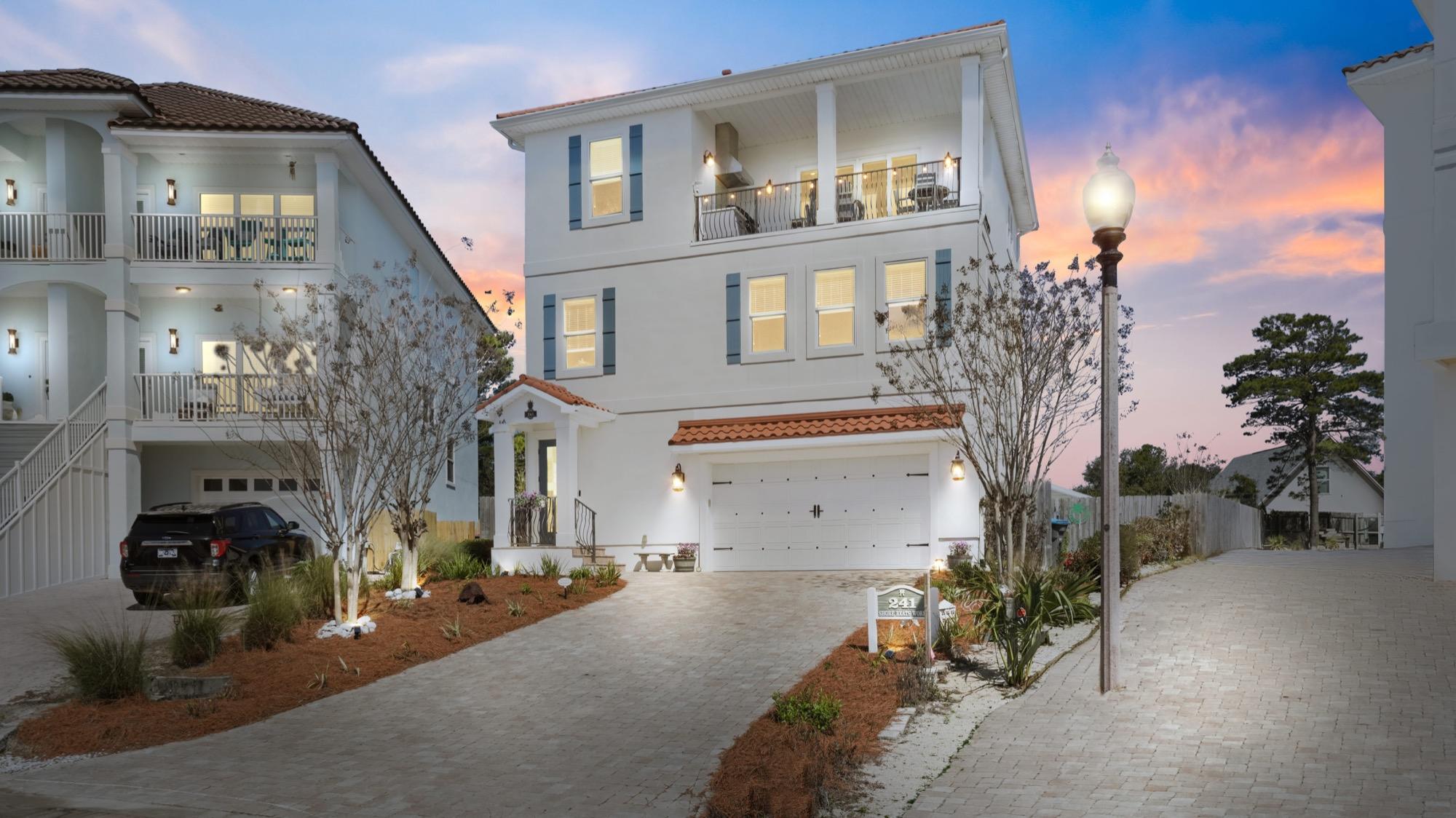 Three-story white coastal home lit up at twilight, photographed on the Florida Panhandle