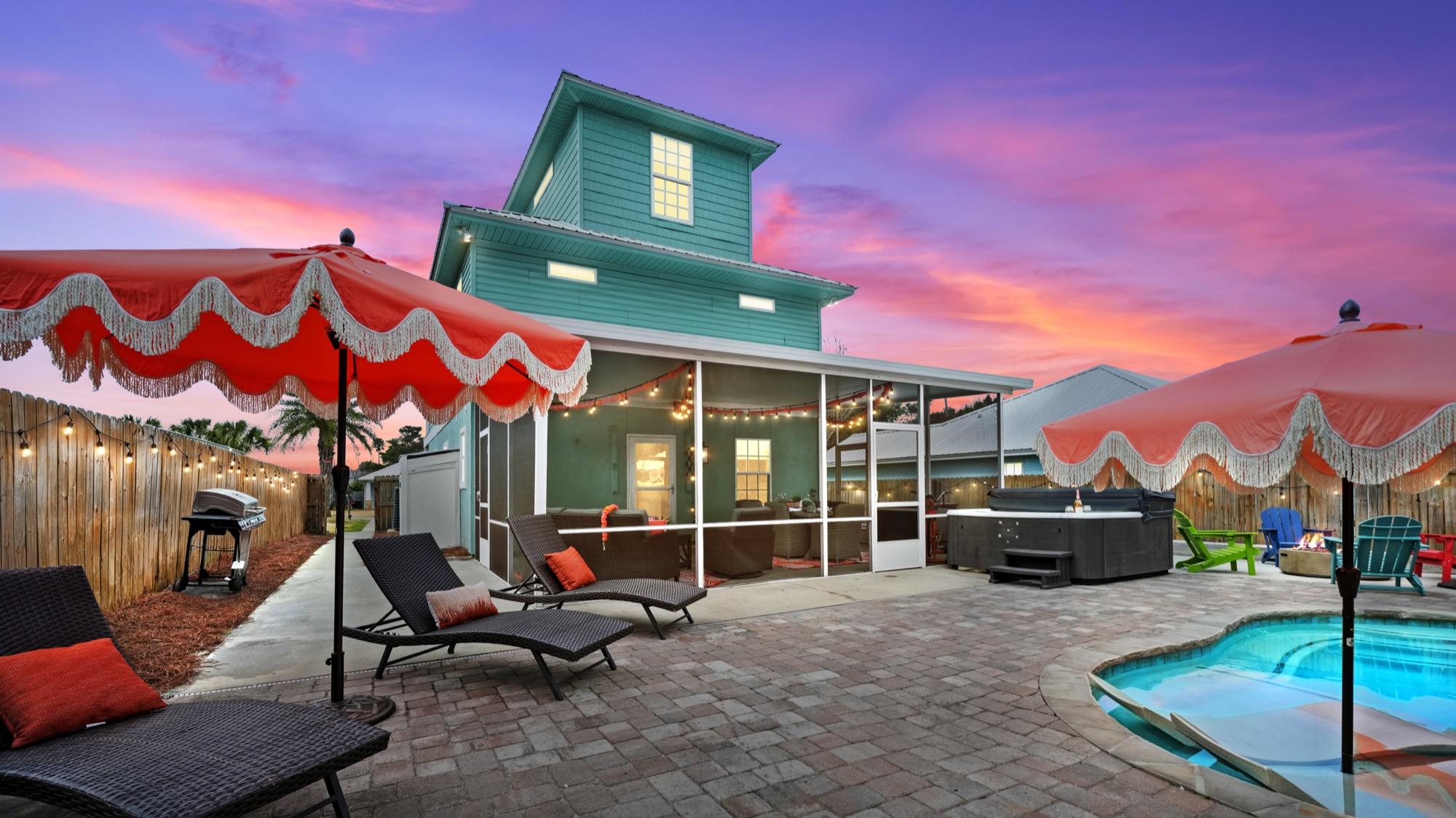 Teal beach cottage with a pool and fringed umbrellas at dusk, photographed on the Florida Panhandle