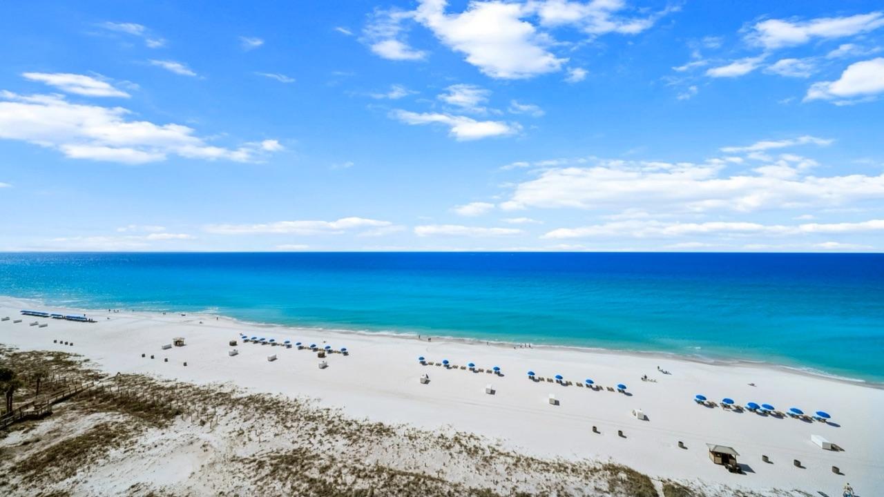 Emerald Gulf water and white sand beach with rows of beach umbrellas, photographed on the Florida Panhandle
