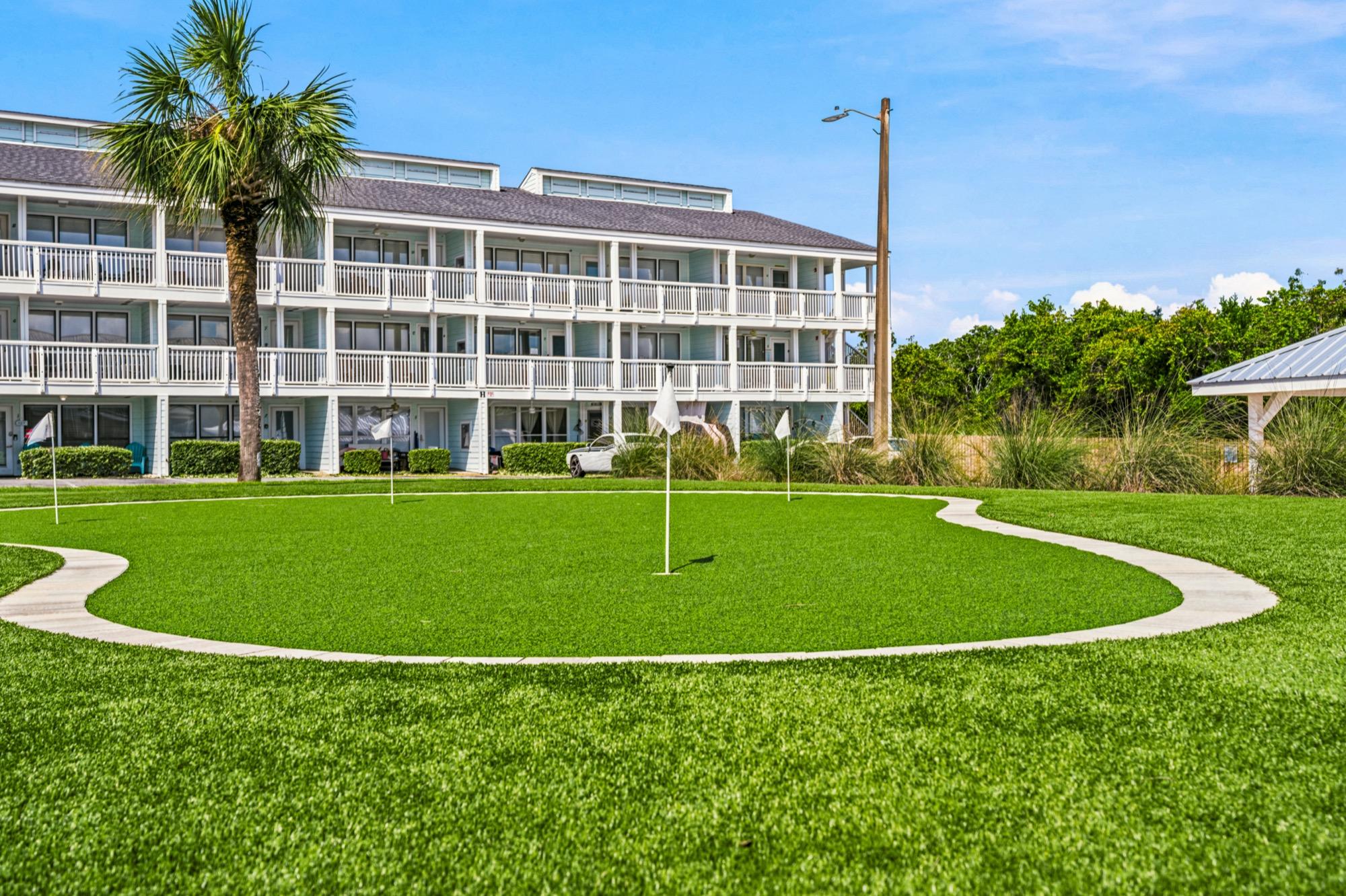 Community putting green on a manicured lawn in front of a condo building, photographed on the Florida Panhandle