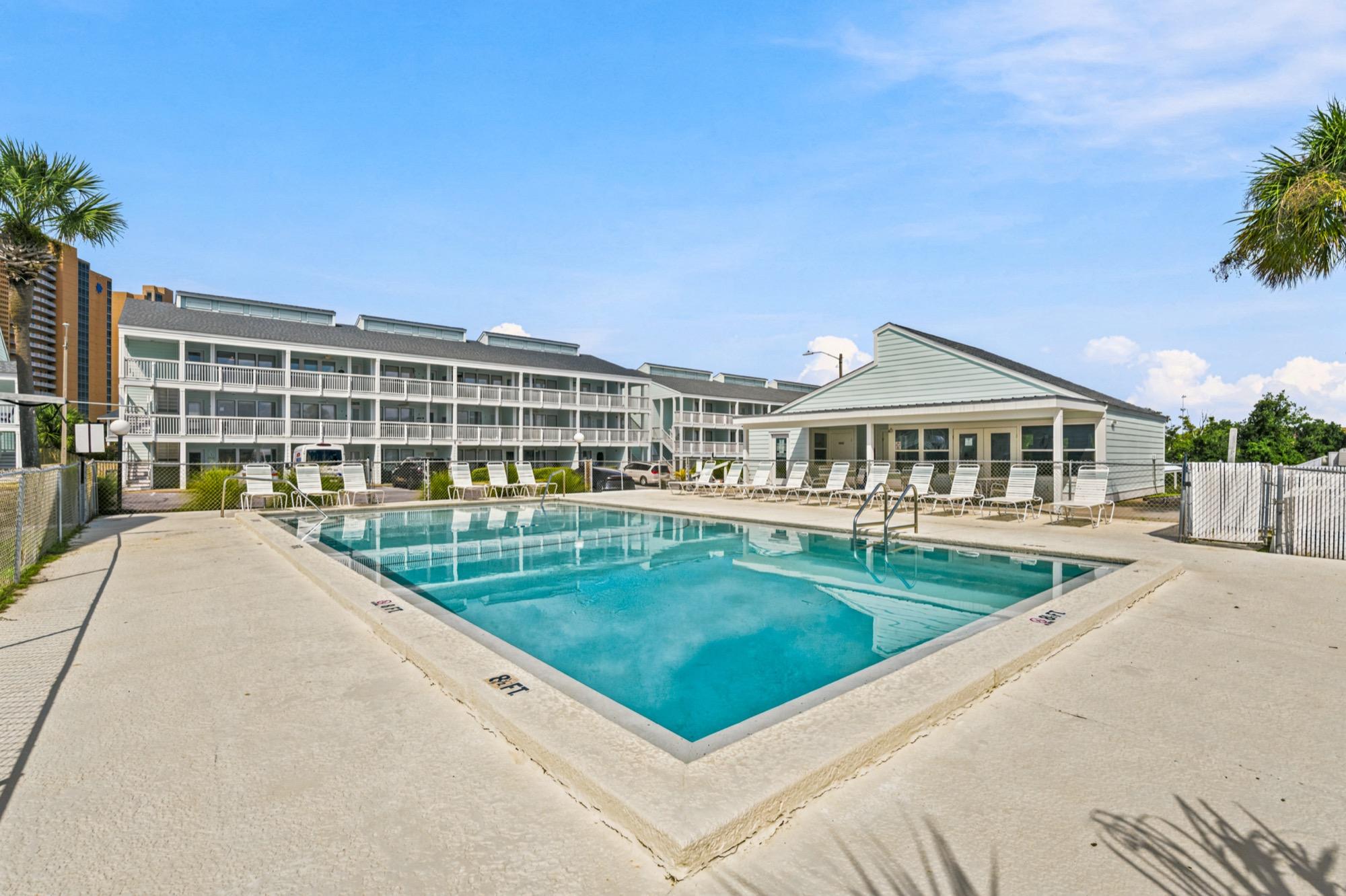 Community pool with lounge chairs, a clubhouse and palm trees, photographed on the Florida Panhandle