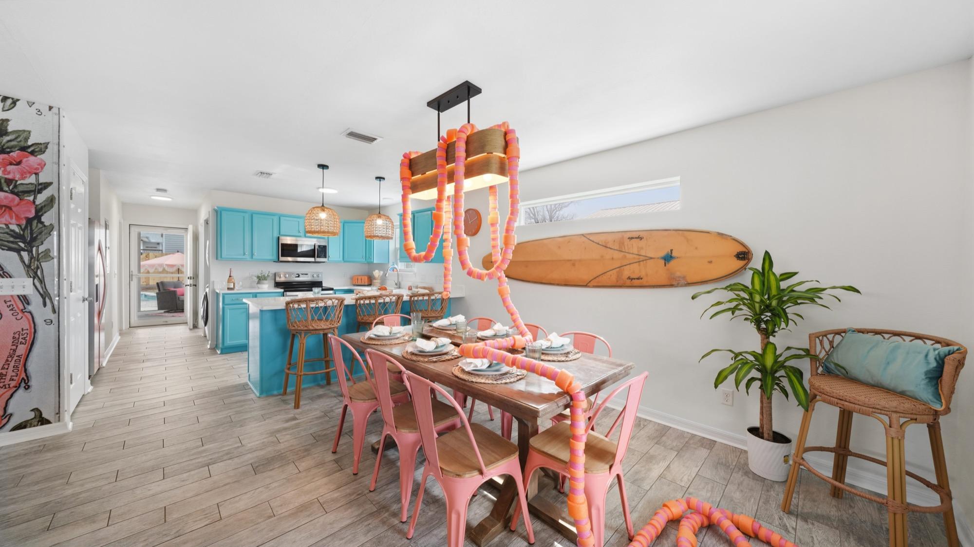 Dining room with a long table, coral chairs and surfboard decor, photographed on the Florida Panhandle