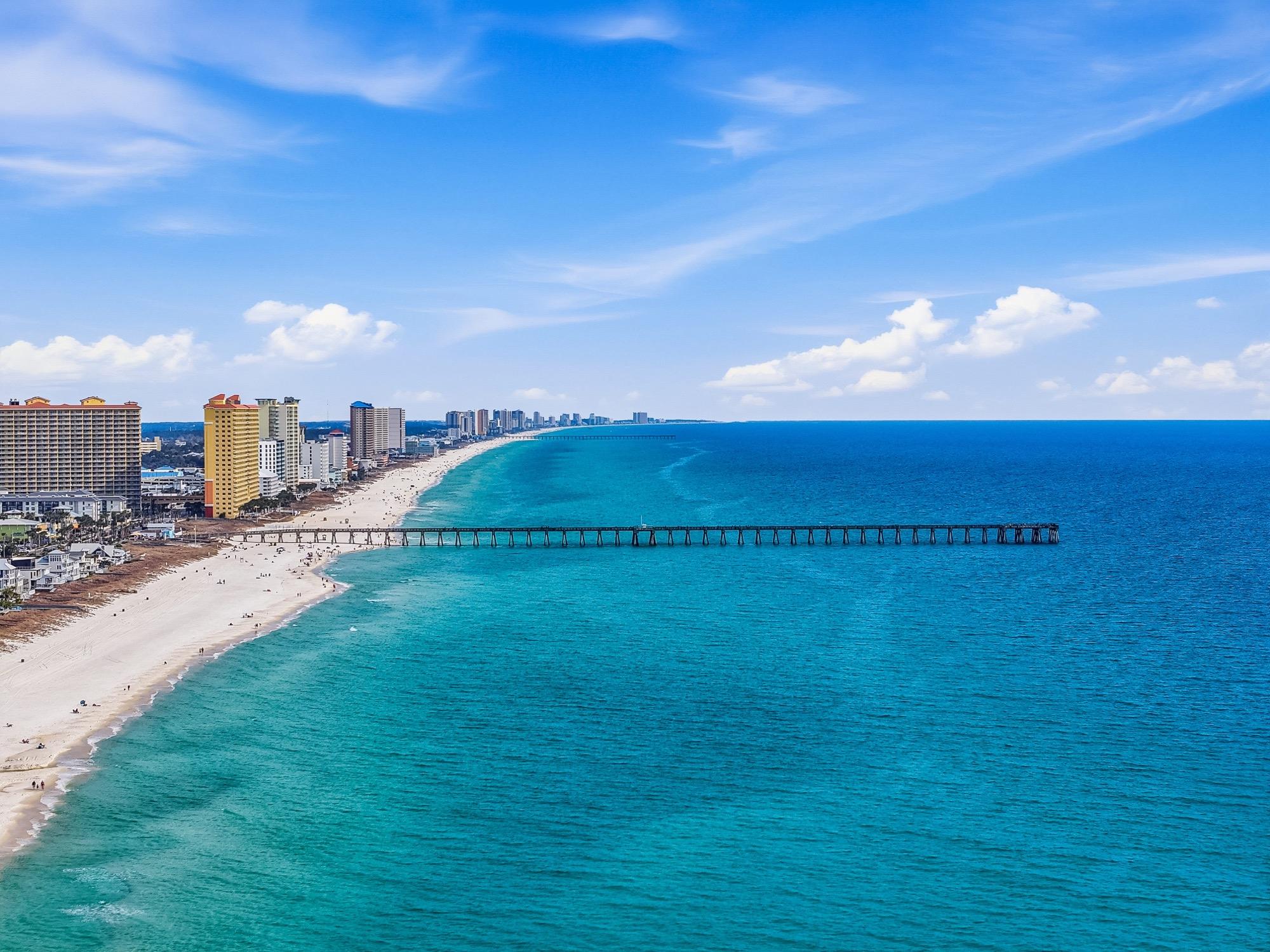 Aerial view of a fishing pier over turquoise Gulf water, photographed on the Florida Panhandle